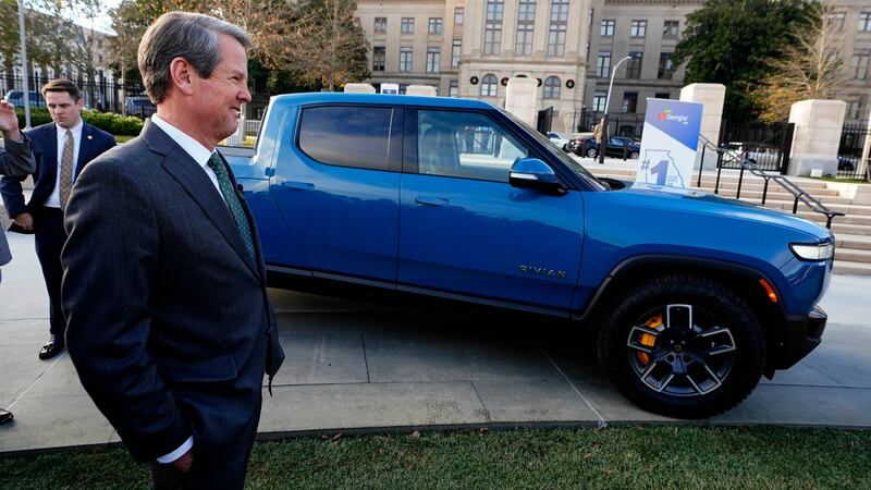 FILE -- Georgia Gov. Brian Kemp stands next to a Rivian electric truck while announcing the...