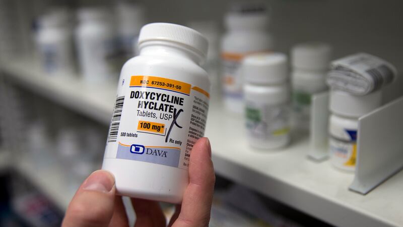FILE - A pharmacist holds a bottle of the antibiotic doxycycline hyclate in Sacramento,...